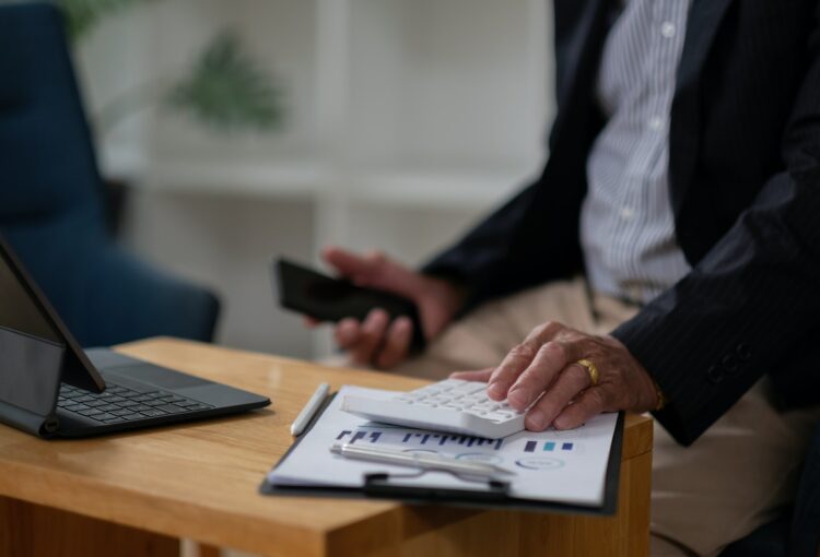 Close up hand of elderly accountant working on desk using calculator for calculate finance report